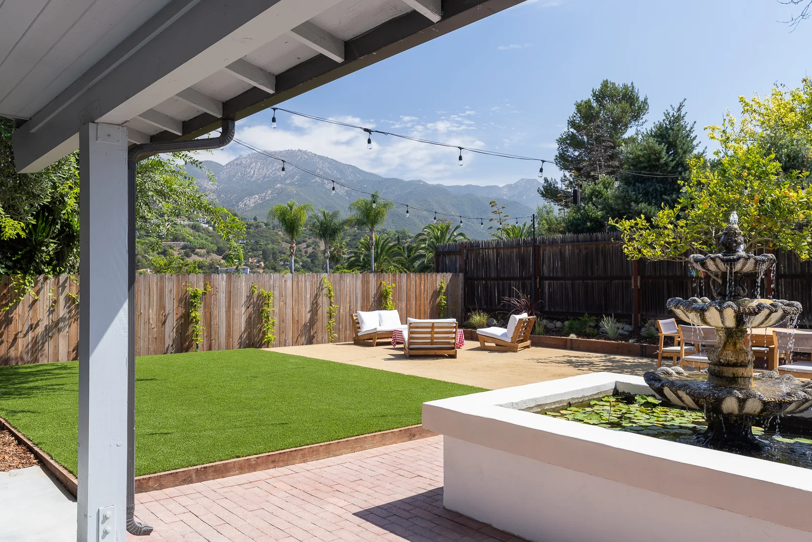 View from the covered patio across the turf lawn to the lounge area, with the lily pond fountain in the foreground