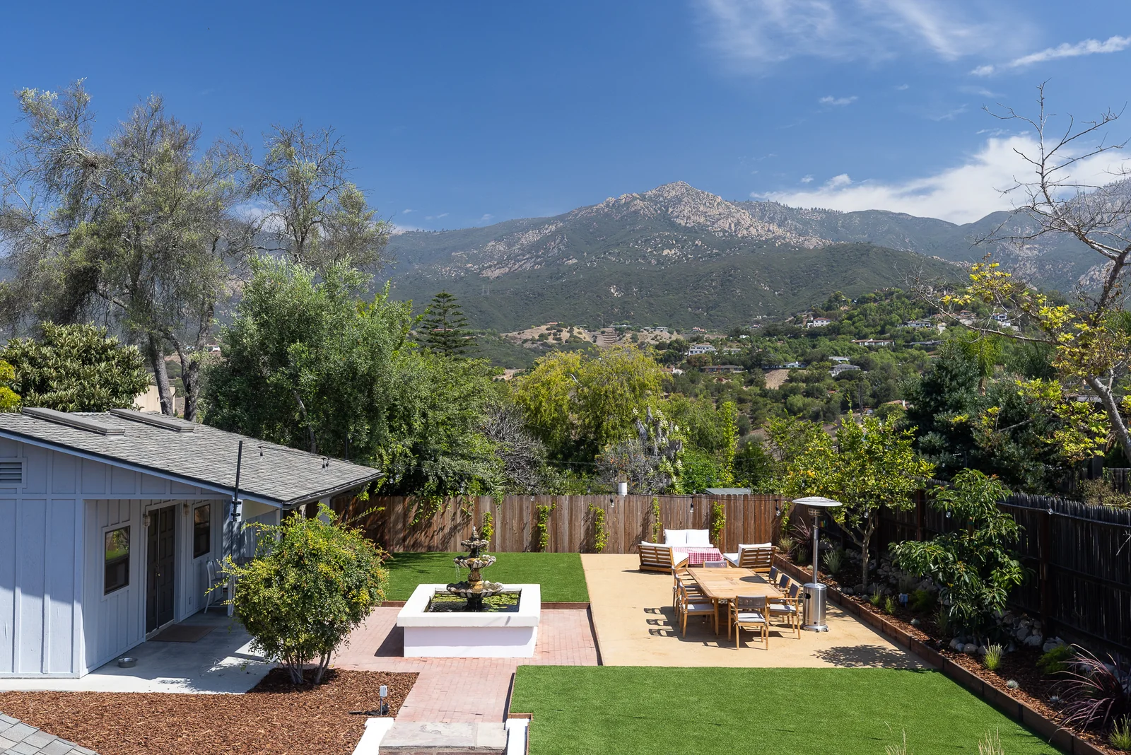 Elevated view of the backyard with brick patio, fountain and dining terrace against the Santa Barbara foothills